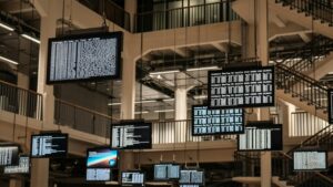 A bunch of televisions screens hanging from the ceiling and displaying data